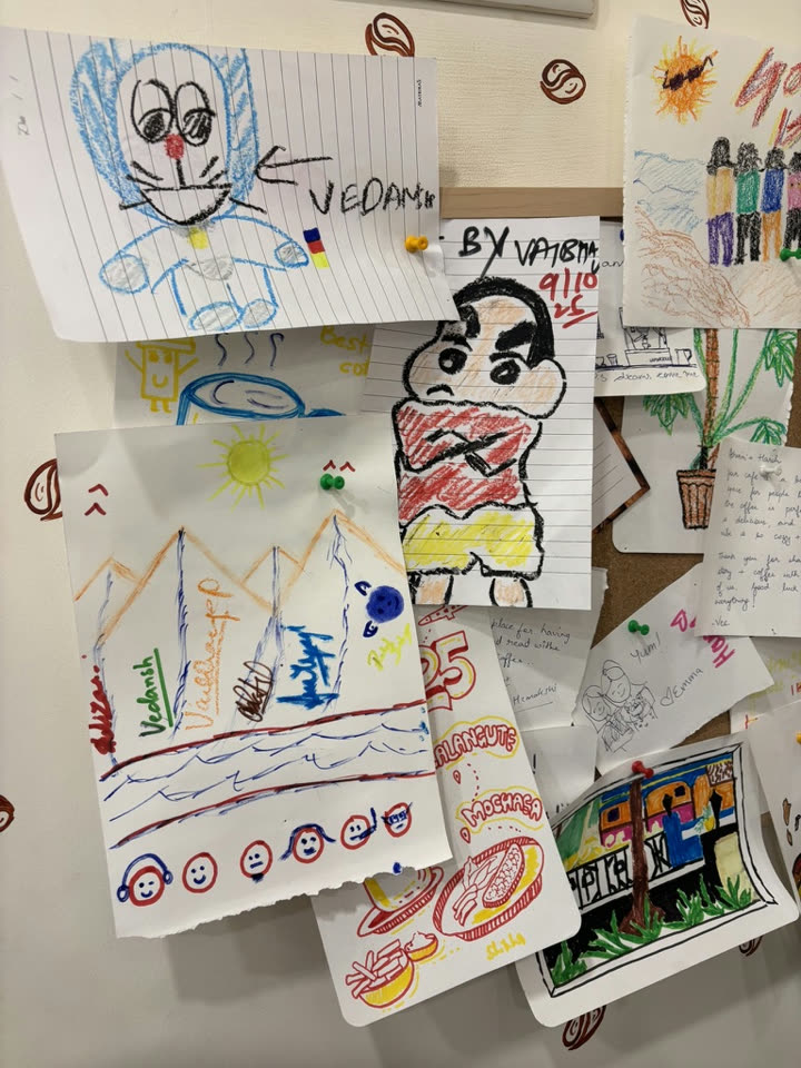 Crayon drawings pinned on a café wall, including a Shinchan signed by Vaibhav