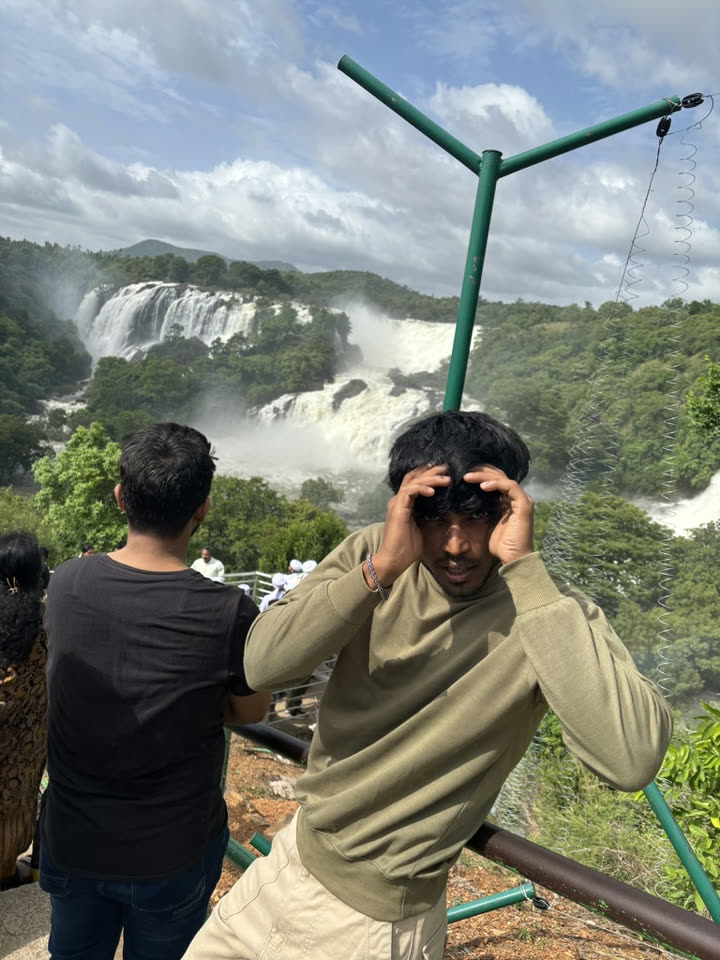 Vaibhav clutching his head in mock panic in front of a waterfall