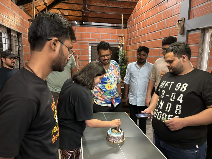 Friends gathered around a table while someone cuts a cake