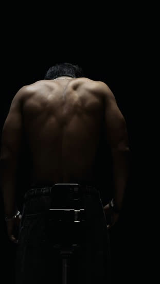 Vaibhav from behind in a dark gym, back lit by a single light