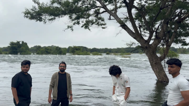 Friends standing in a flooded river under a big tree